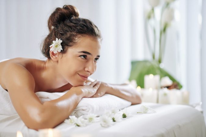 Jeune femme relaxée sur une table de massage lors d'un rituel bien être au spa.