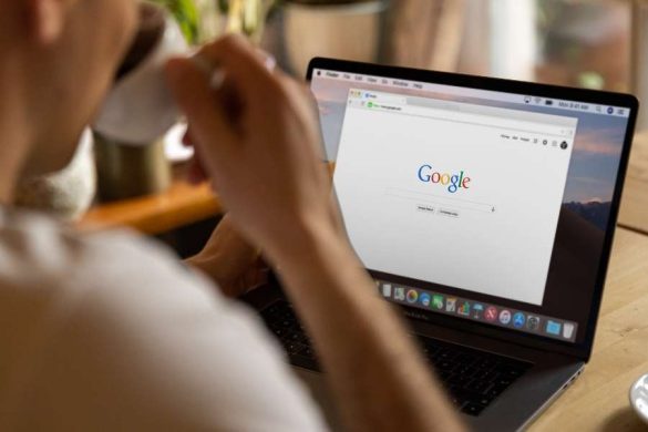Gros plan sur un homme buvant un café face à son ordinateur affichant la page d'accueil de Google.