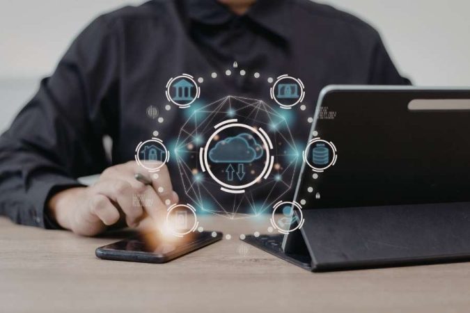 Un professionnel utilise son smartphone à côté d'une tablette avec une interface cloud lumineuse.